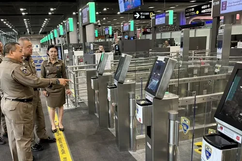 Immigration officers inspecting a row of biometric e-gate kiosks at Suvarnabhumi Airport